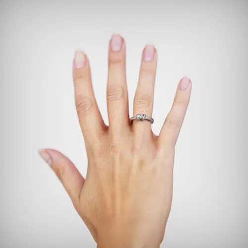 Anillo de compromiso IRIS en oro blanco 18k Fairmined o platino responsable 950 con diamante de 20 o 25 puntos, mostrado en una mano femenina