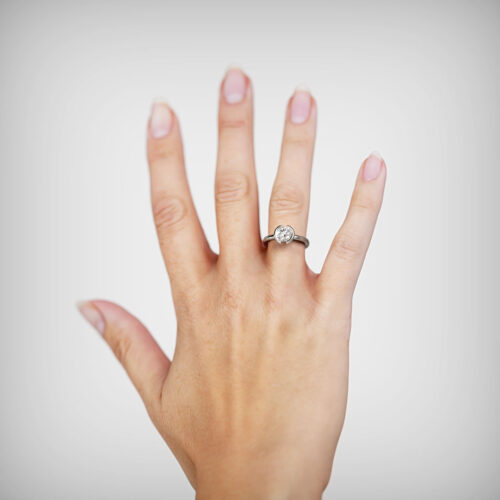 Anillo de Compromiso Solitario Isis Oro Blanco 18kt Anillo de compromiso ISIS en oro blanco 18k Fairmined o platino responsable 950 con diamante de 100, 150 o 200 puntos de origen en laboratorio, mostrado en una mano femenina