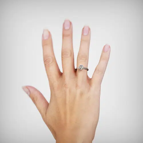 Anillo de compromiso PLUVIA en oro blanco 18k Fairmined o platino responsable 950 con diamante de 50, 100 o 150 puntos de origen en laboratorio, mostrado en una mano femenina